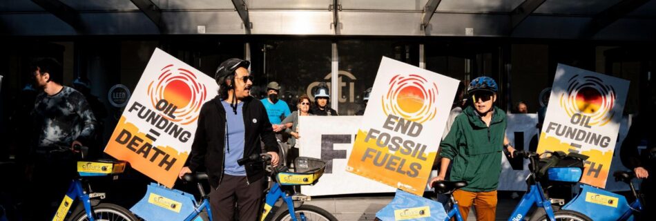 A group of Summer of Heat protestors with decorated Citi bikes blocking the doors to citi bank